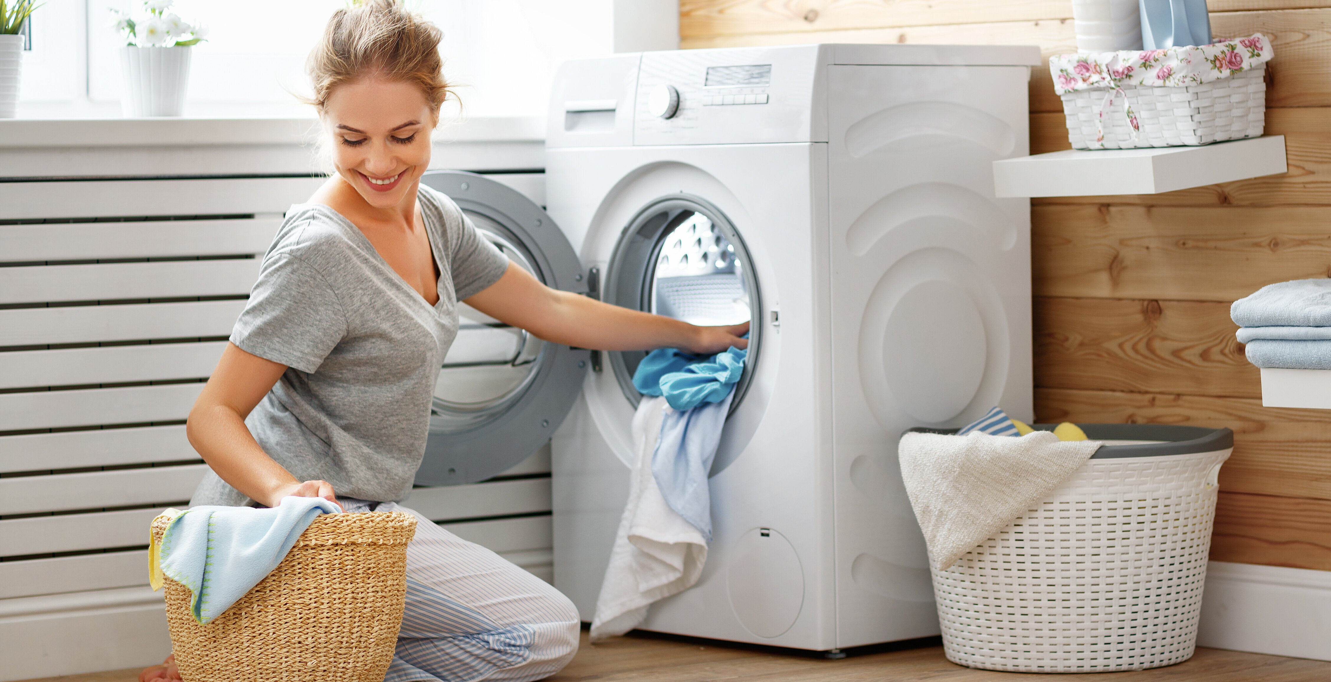 Happy housewife woman in laundry room with washing machine